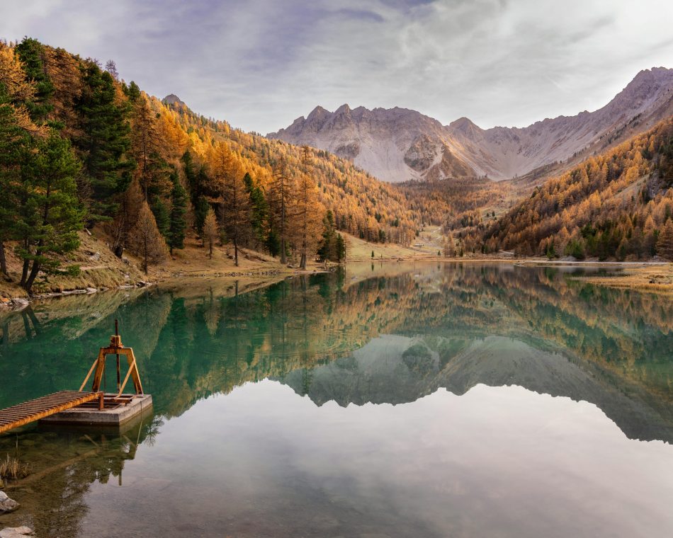 Stunning autumn landscape with reflection at Serre-Ponçon Lake in the French Alps.